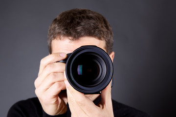 Photographer with a camera, focus is on the lens