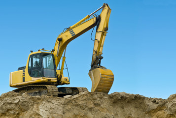 Yellow excavator on sand hill
