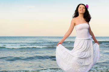 Fototapeta na wymiar The woman in a white sundress on seacoast.