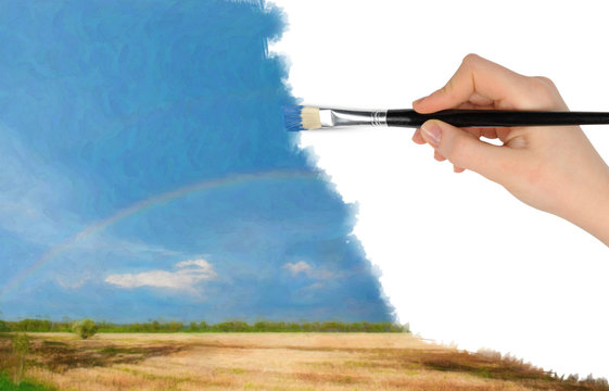 The hand with a brush draws a landscape.