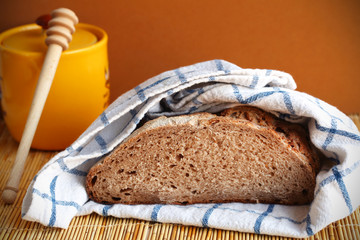 Fresh loaf of rye bread in kitchen towel, with honey jar