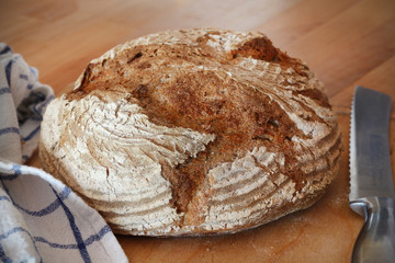 Loaf of rustic rye bread with a kitchen towel and bread knife