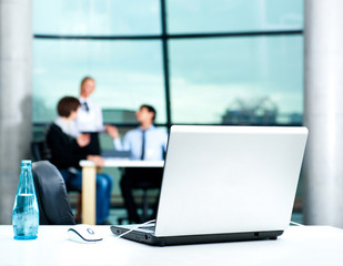 Modern laptop on foreground at empty workplace