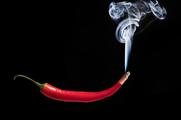 Smoking red hot chilli pepper with burning tip and smoke