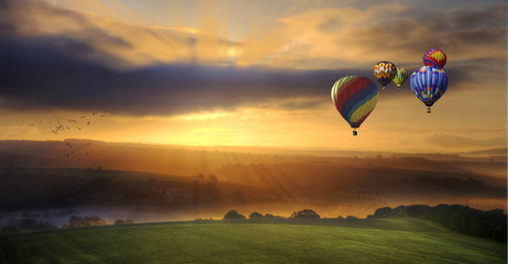 Stunning sunrise of hot air balloons over South Downs landscape