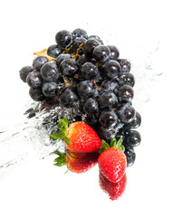 brunch of grapes and two strawberries in water splash