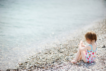 Cute toddler girl on pebble beach