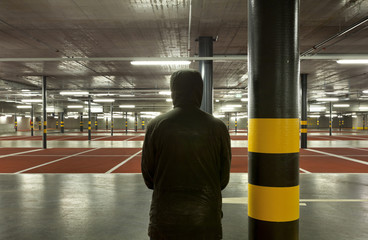 new underground parking, back view of shady man.