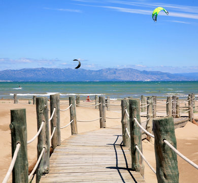 Wooden stairs and kite surfers on the beach Riumar Spain