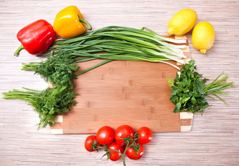 Kitchen chopping board with vegetables, a tomato and a lemon