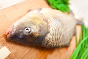 Fresh fish on a kitchen board with vegetables.