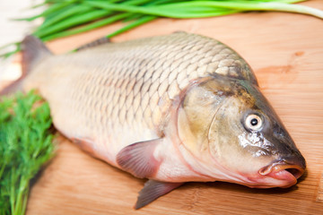Fresh fish on a kitchen board with vegetables.