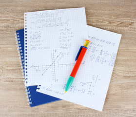 Math, physics and geometry on copybook page on a wooden table