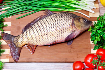 Fresh fish on a kitchen board with vegetables.
