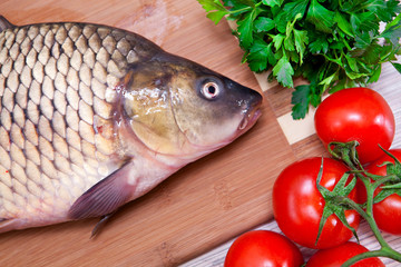Fresh fish on a kitchen board with vegetables.