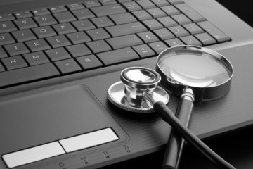 Stethoscope and magnifying glass on laptop
