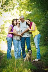 Naklejka na ściany i meble Family portrait - Family of four with a cute dog outdoors