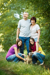 Naklejka na ściany i meble Family portrait - Family of four with a cute dog outdoors