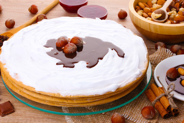 cake on glass stand and nuts on wooden  table