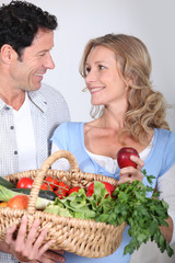 Couple looking into each other's eyes with vegetable basket.