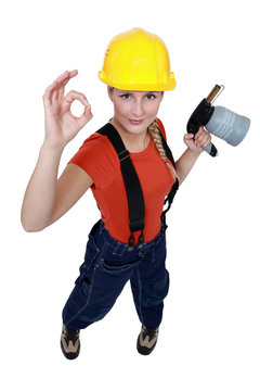 Tradeswoman holding a blowtorch and giving the a-ok sign