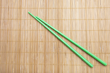 Green chopsticks on bamboo mat