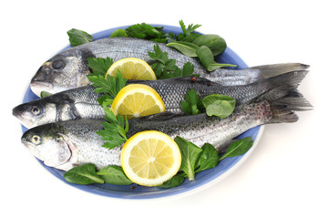 Fresh fishes with lemon and parsley on plate isolated on white