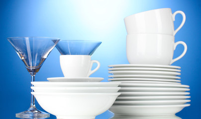 empty bowls, plates, cups and glasses on blue background