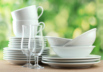 Clean dishes on wooden table on green background
