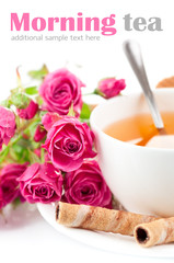 tea in cup with biscuits and bouquet roses