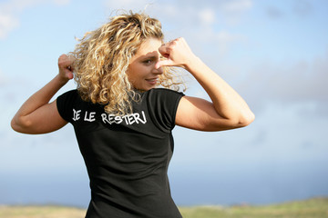 Blond woman in field pointing at t-shirt