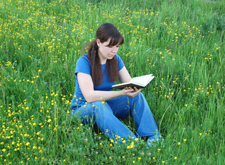 Young woman reading a book at the meadow