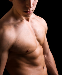 Fototapeta premium torso of young muscular man, isolated on black background