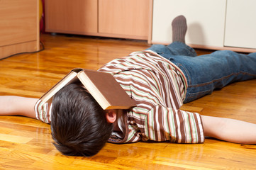 Teenage boy sleeping on the floor with book covering his face