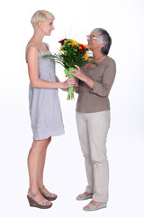 Young woman giving an elderly lady flowers