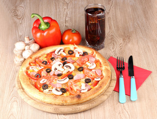 Aromatic pizza and cola on wooden background