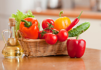 Healthy food fresh vegetables in basket and bottle with oil on t