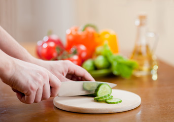 Preparing vegetable salad on kitchen table. Focus on the finger.
