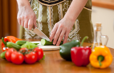Preparing actions for vegetable salad on kitchen table. Focus on
