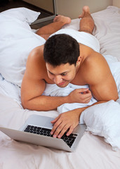 Young man using laptop at the bedtime