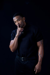 black man in black shirt, with finger over lips