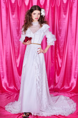 Bride in a white wedding dress on a pink background