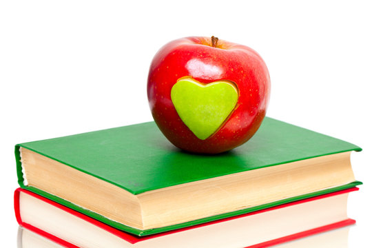 apple with green heart on stack of books