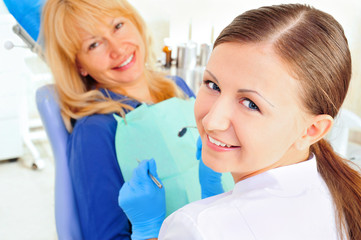 At dentist's office young nurse with adult mature woman
