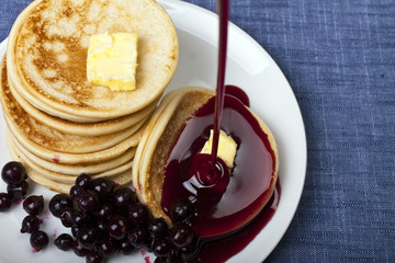 Pile of pancakes on a plate with a bilberry and jam
