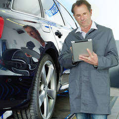 Master mechanic in a garage working with touchpad