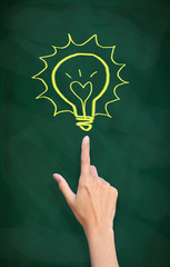 finger point to light bulb drawn on blackboard