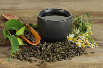 Tea - cup, green leaf and camomile on background