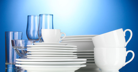 empty bowls, plates, cups and glasses on blue background