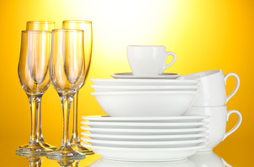 empty bowls, plates, cups and glasses on yellow background